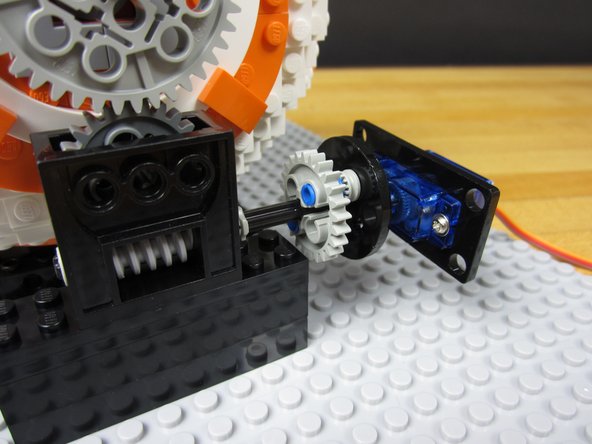 Connect the round Servo Horn (laser cut disc) to the Servo. Using a couple of technic pieces and a gear, build out an adaptor on the end.