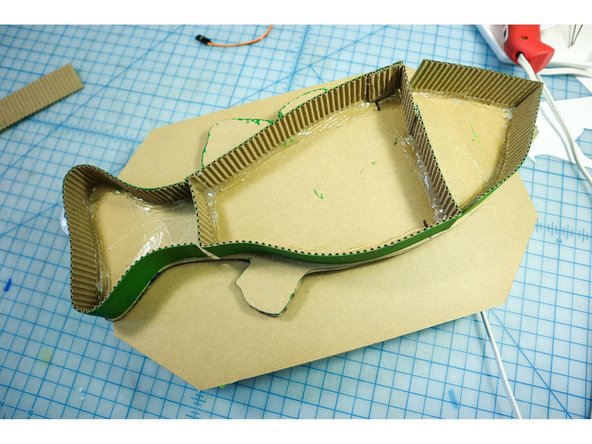 Using hot glue, carefully line the perimeter of the fishtail, the center of the body, and the head as shown. The center section should have a vertical wall as well to connect to the plaque. The three segments are necessary for the head and tail to move.
