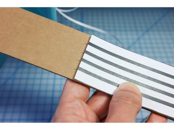 Thread the pieces through from the front and stick each string in place.