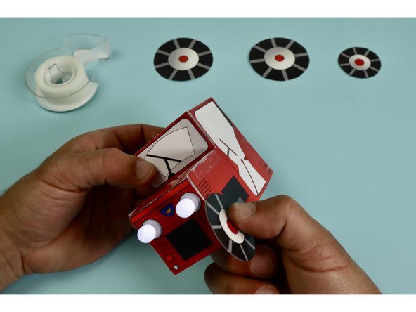 Make loops of clear tape for the two small wheels and attach them to the front of the tractor where it says &quot;clear tape.&quot;