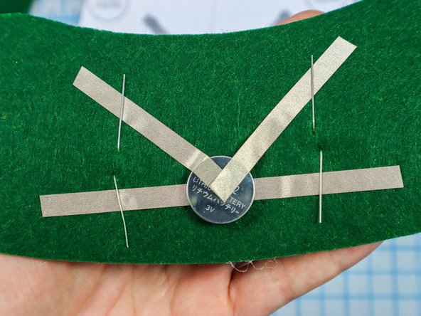 Fold each LED leg down flat against the felt, making sure the longer, positive legs touch the &quot;V&quot; and the shorter, negative legs touch the horizontal piece.