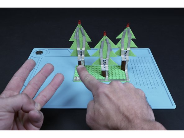 Create single shorter paths that connect to the tape leading from each of the 3 long LED legs (they should be on the left when viewed from the back), down the tree and to the edge of the 90 degree LEGO pieces.