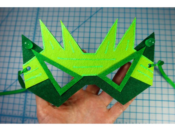 Add a green ribbon to the mask to keep it on the wearer's head.
