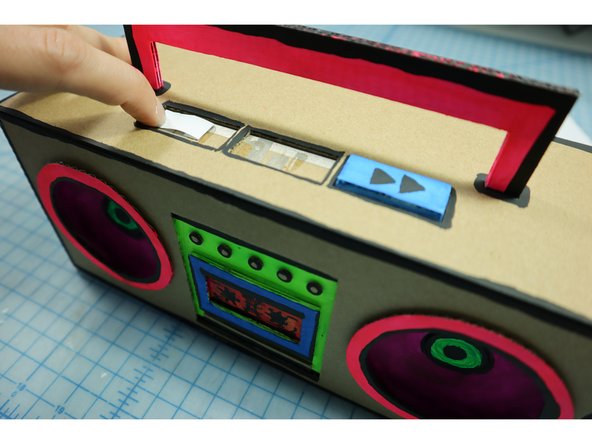 Add glue to the flaps and place the piece over the gap in the Maker Tape so that pressing down on the paper closes the switch.