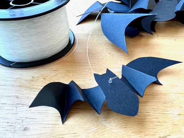 Thread about 2 feet of fishing line through the hole on each bat and tie a knot to keep it in place.