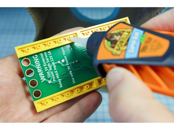 Add superglue to the bottom of the LEGO and place it in the bottom of the guitar, pushing it all way back against the guitar body.