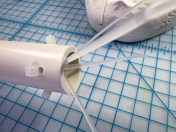 Drill four holes in the skull and a PVC pipe, then connect the pipe as shown with zip ties.