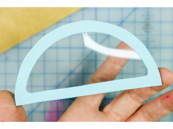 Use hot glue to secure the plastic inside the window of the box. A few dabs of glue will work, just be sure to keep the glue away from the edge so that you can't see it from the front.