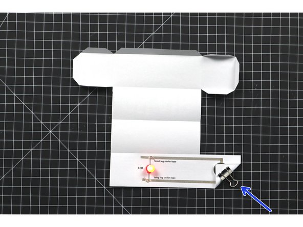 Fold the &quot;switch&quot; corner down on top of the battery so the positive side of the circuit is complete.
