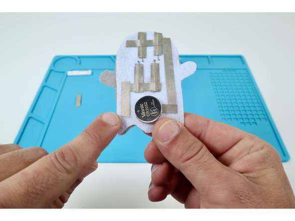 The first path should go across both of your long legs toward the left edge of the felt embellishment. Make sure the right end of it does not contact any part of the path leading from the Short LED Legs.