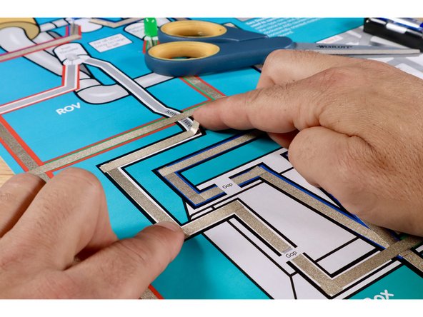 To prepare the White LED, first orient the legs so that the Long Positive (+) Leg is on the left. Next, fold the legs flat and then in a &quot;V&quot; so that it can sit in position atop the poster. NOTE: This step is not pictured. Use the same process used to prepare the Blue LED for this LED in ITS location.