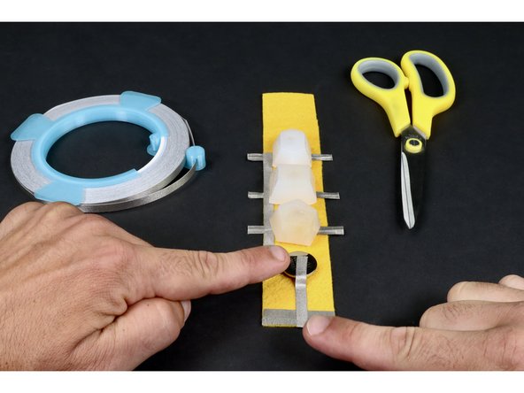 Measure, cut, peel and stick another Maker Tape segment that reaches from the top of the battery all the way to the two overlapping pieces from the previous step.