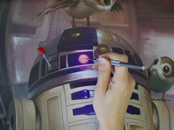 Use a safety pin to make two holes for the LED legs to poke through the poster.