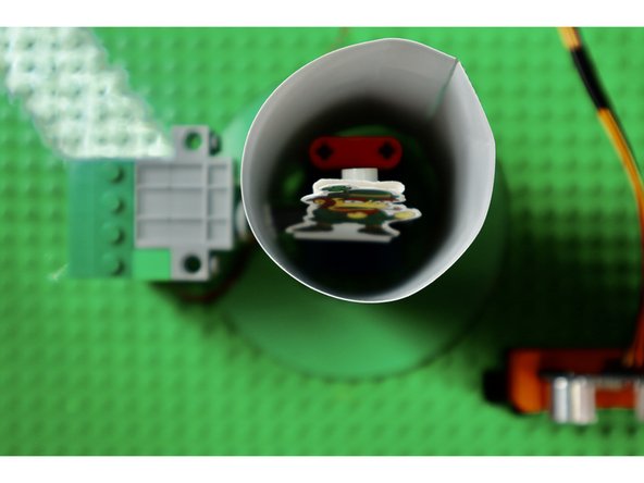 Now do the same with the tube; belt and buckle first. You do not need to attach the brim to the hat tube. Rotate the tube so that the hole you removed for the axle lines up with the axle. Then reattach the servo axle and the axle inside the tube through the hole.