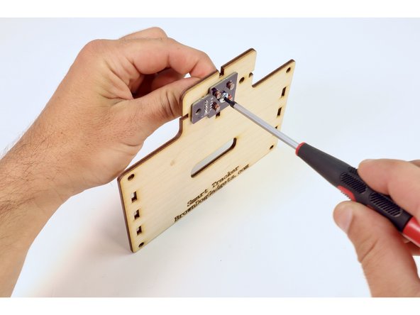 Thread the 1/2" screw through the hole between the four photoresistors and, using the nut and the screwdriver, tighten to secure the circuit board to the wooden plate.