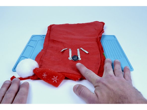 Stick the battery to the tape loop so the positive (+) side faces UP.