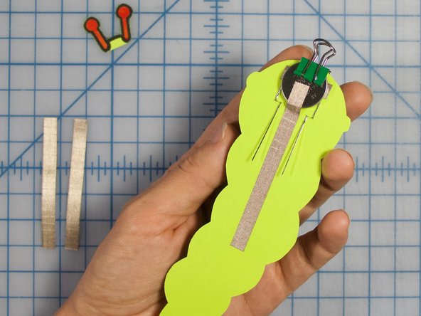 Stick the longer, 3 inch piece of Maker Tape to the back of the battery. Make sure this piece of tape doesn't touch the positive legs of the LEDs.