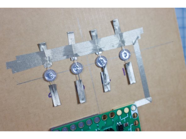 Connect a piece of Maker Tape to the Ground Pin and run it across the ground leg of all 4 LEDs. Add extra Maker Tape to secure it.