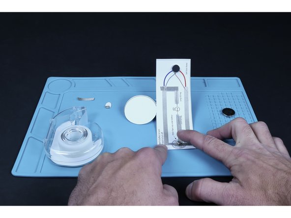 Press the battery atop that tape loop so that the positive (+) side faces UP.