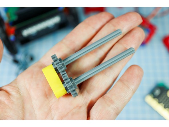 Insert 2 axles with flat ends into the outer holes of the yellow beam, and thread on the gears.