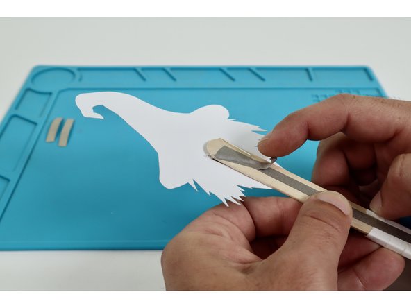 Using two of  your three Maker Tape pieces, stick one atop each of the two LED legs bent flat in the previous step. Press them into contact with the upward-facing long handle path.