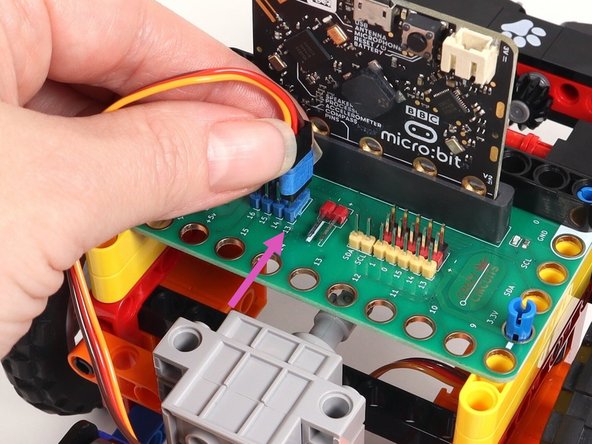 Plug the left servo connector into the row for Pin 13 of the blue 5V pins. The orange wire should go to the pin closest to the 13 on the board, the red wire goes into the +5v row, and the brown wire goes into the - row, which is ground.