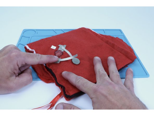 Measure, cut, peel and stick one final piece of Maker Tape that will span the distance between the positive (long leg) Maker Tape pad and the top of the battery.