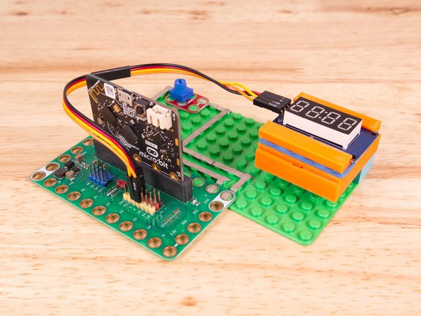 Now we'll connect the other end of the Ribbon Cable to the 7 Segment Display. The pin labels are on the back of the 7 Segment Display PCB. From top to bottom it's CLK, DIO, VCC, GND.