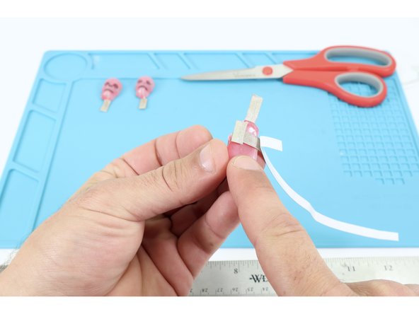 First measure and cut a 6-7&quot; long section of Maker Tape and peel one end of it back enough to stick it to the top part of the pad for the short, negative leg of one of your molded LEDs. The new path will be BETWEEN the surface of the glue on the back of the object and the LED leg, sticky side down if looking at the front of the molded object.