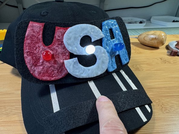 Slide your finger over the piece of felt on the brim - when you are near the &quot;U&quot; the red LED will light, the &quot;S&quot; the white LED will light, and the &quot;A&quot; the blue LED will light.