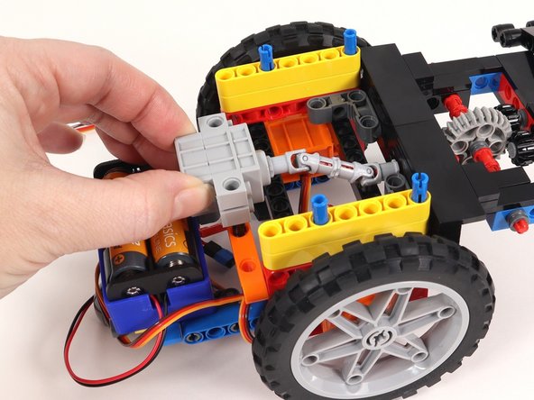 Connect the two black pins on the servo to the orange beam with side holes on the back of the Rover. The wires should be facing the bottom of the Rover.
