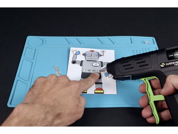 With a glue gun, apply a small dot of glue where indicated in the first photo.