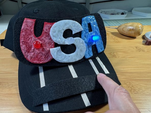 Slide your finger over the piece of felt on the brim - when you are near the &quot;U&quot; the red LED will light, the &quot;S&quot; the white LED will light, and the &quot;A&quot; the blue LED will light.