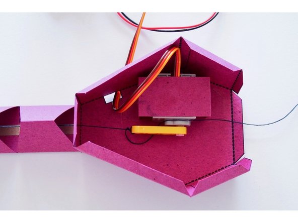 Tie the string to the end of the LEGO Beam in such a way that it is lightly tensioned when the mount faces towards the tail, and tight enough to pull the tail up when the beam points away from the tail.