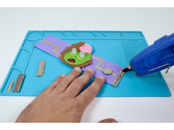 Use a hot glue gun to put a small bead of glue atop the edge pad on each side of the tape loop. Do not put glue on the tape loop.