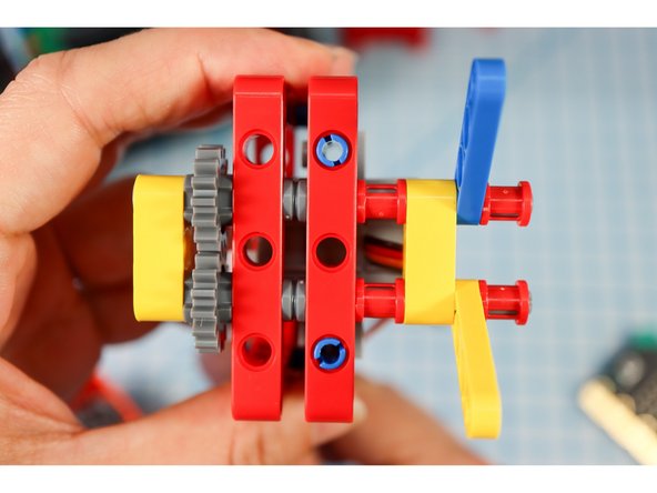 Insert two red full bushings, another yellow beam, two half beams (one on each axle), and two more red full bushings as shown.