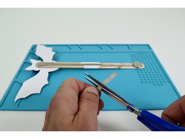 Finish installing the battery and turn the LEDs on.  To do this, measure, cut, peel, and stick a piece of Maker Tape that can reach from the top of the battery  around to the path on the opposite side of the wand handle.