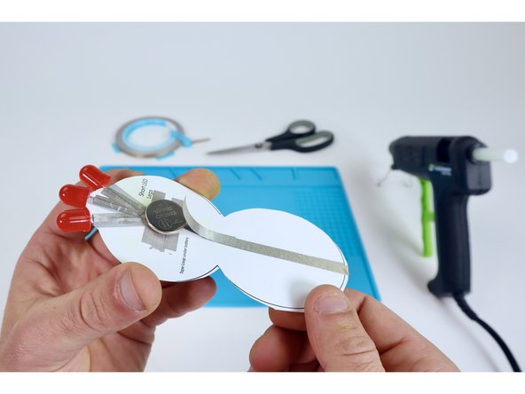 Now, peel &amp; stick Maker Tape segment “K” so one end connects to "G" and the other connects to the top of the battery. This completes the circuit and turns the LEDs on.