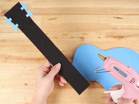 Using hot glue or another strong glue, attach the neck  to the body of the guitar.