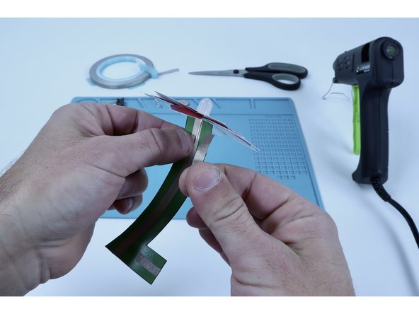 Using your free hand, stick that already peeled Maker Tape segment over the top of the short leg so that it is sandwiched between Maker Tape and held in place.