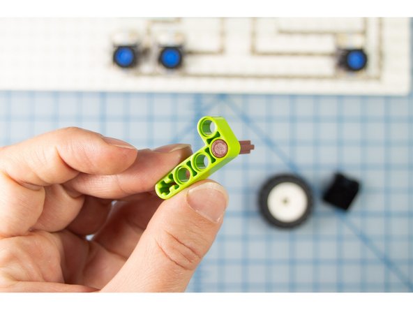 Insert the axle with end stop piece through a hole in a Technic beam or bent beam piece.