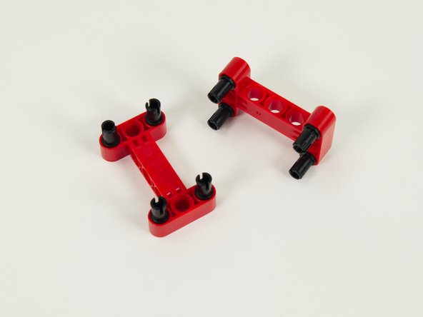 Insert four black pins into each of the red I-shaped beams as shown.