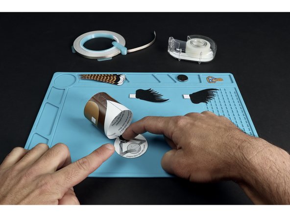 First, use two Maker Tape sections to secure the two motor wires in place. Then, add the Maker Tape section shown so that it sits atop the battery graphic and connects to the tape path leading from the RED wire of the motor.
