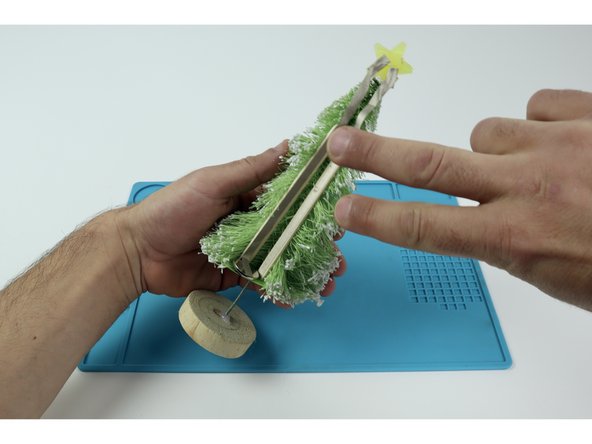 We hot-glued a molded star LED at the top of a craft tree and wanted to place the battery down low in a stable place. This means we needed to solve two problems: creating a stable place below for the battery to be mounted upon horizontally and adding something between it and the LED that pathways can stick to.