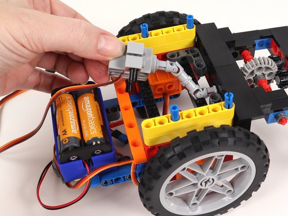 Connect the two black pins on the servo to the orange beam with side holes on the back of the Rover. The wires should be facing the bottom of the Rover.