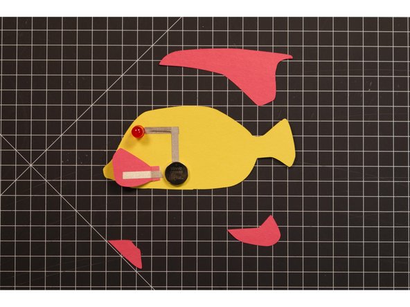 Add a piece of Maker Tape to the fin as shown. It should line up with the battery so it will make contact when the fin is folded over. This is our switch, which completes the circuit, allowing current to flow.