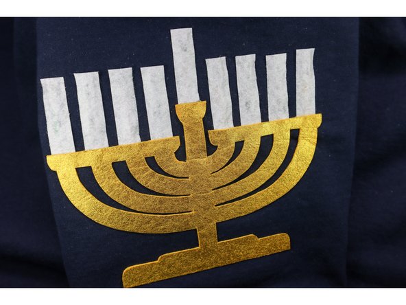 Hot glue the candles in place. Tuck the bottom behind the menorah, and pay attention to the top of each candle to be sure it is even and straight.