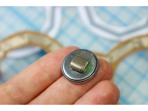 Make a small loop of Maker Tape with the adhesive side out as shown, and place it on the Negative side of the battery.