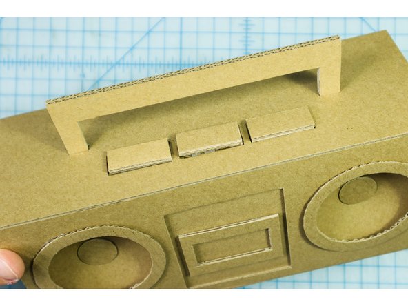 Cut one or two handle pieces from cardboard (depending on how thick the cardboard you are using is) and glue the handle in place.