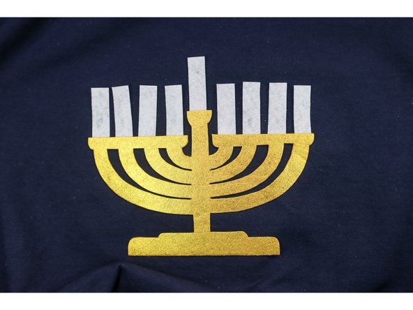 Hot glue the candles in place. Tuck the bottom behind the menorah, and pay attention to the top of each candle to be sure it is even and straight.